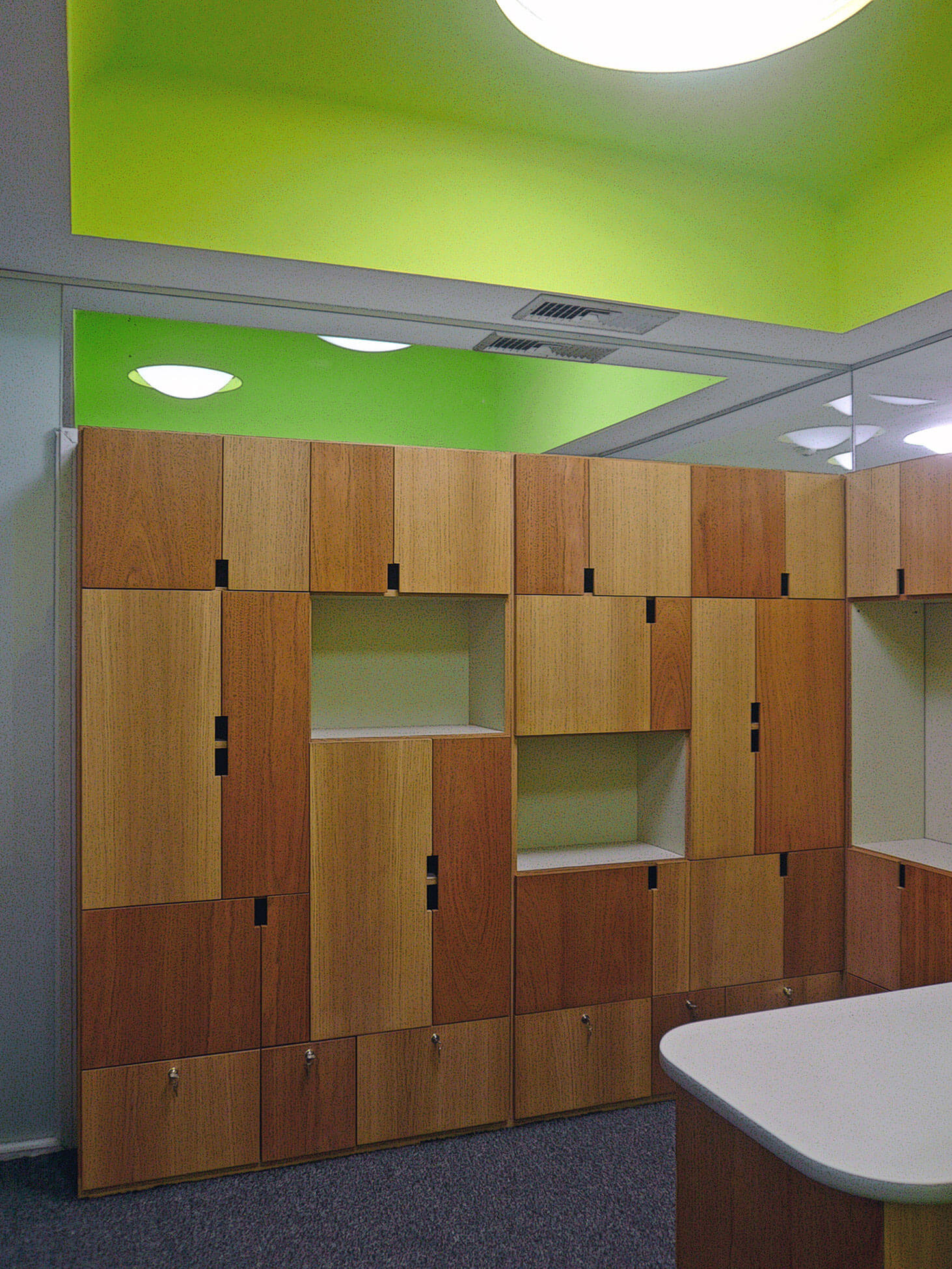 Soluciones con muebles de diseño de madera y techos de colores para optimizar el espacio en la reforma de oficinas