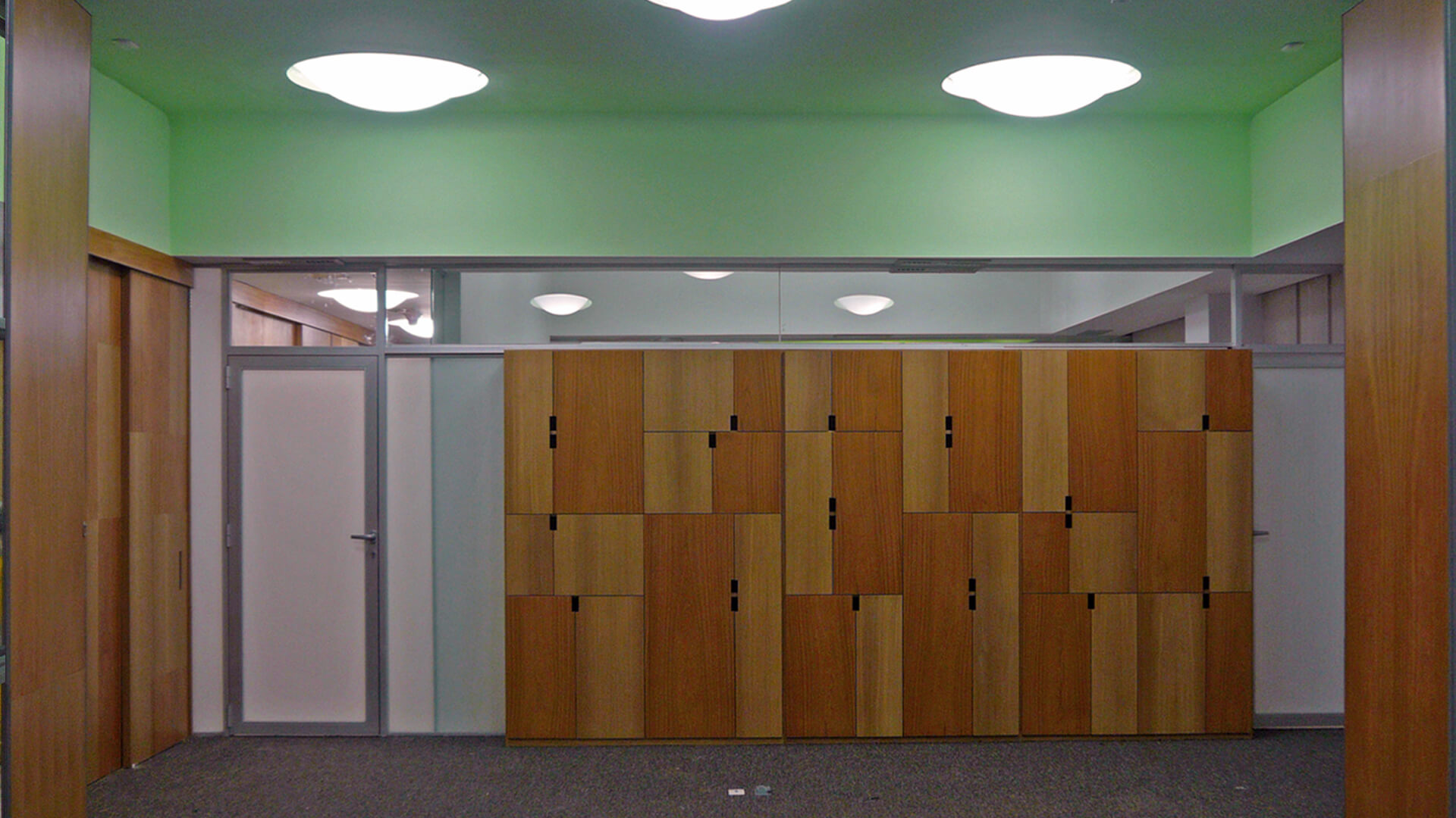 Obra terminada de la reforma de las oficinas de Medifarm: los muebles de diseño de madera mostrando sus puertas cerradas