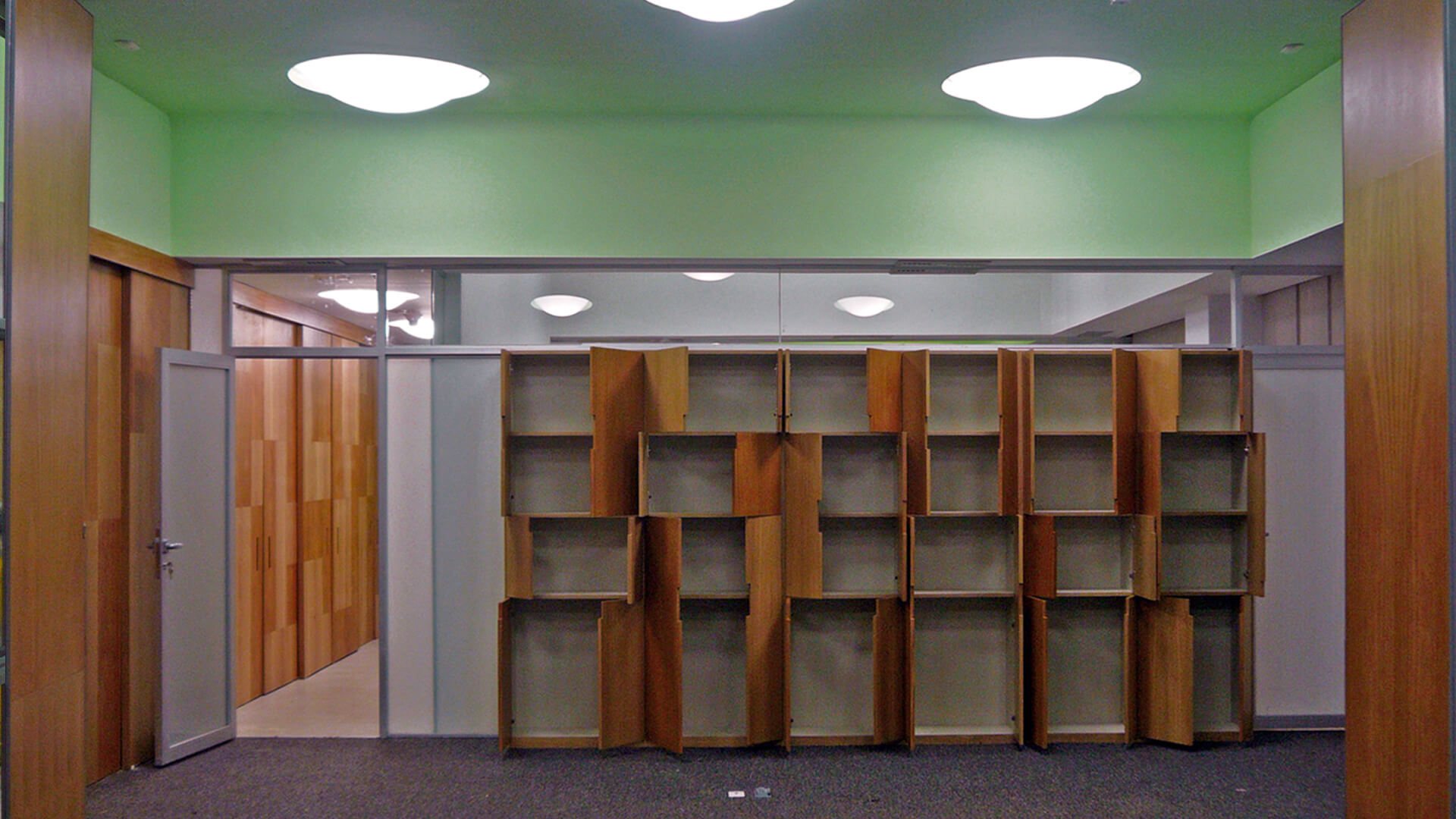 Obra terminada de la reforma de las oficinas de Medifarm: los muebles de diseño de madera mostrando sus puertas abiertas