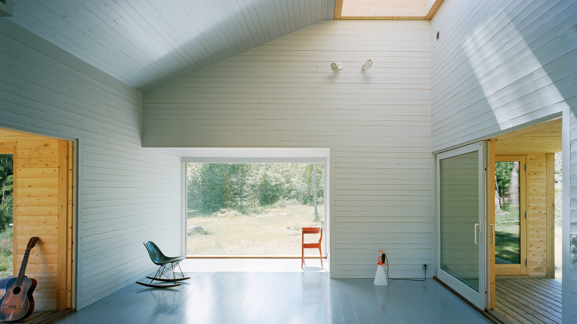 Casas pequeñas: Sala de estar con revestimiento de madera y gran ventanal en la vivienda de verano en Söderöra, Suecia