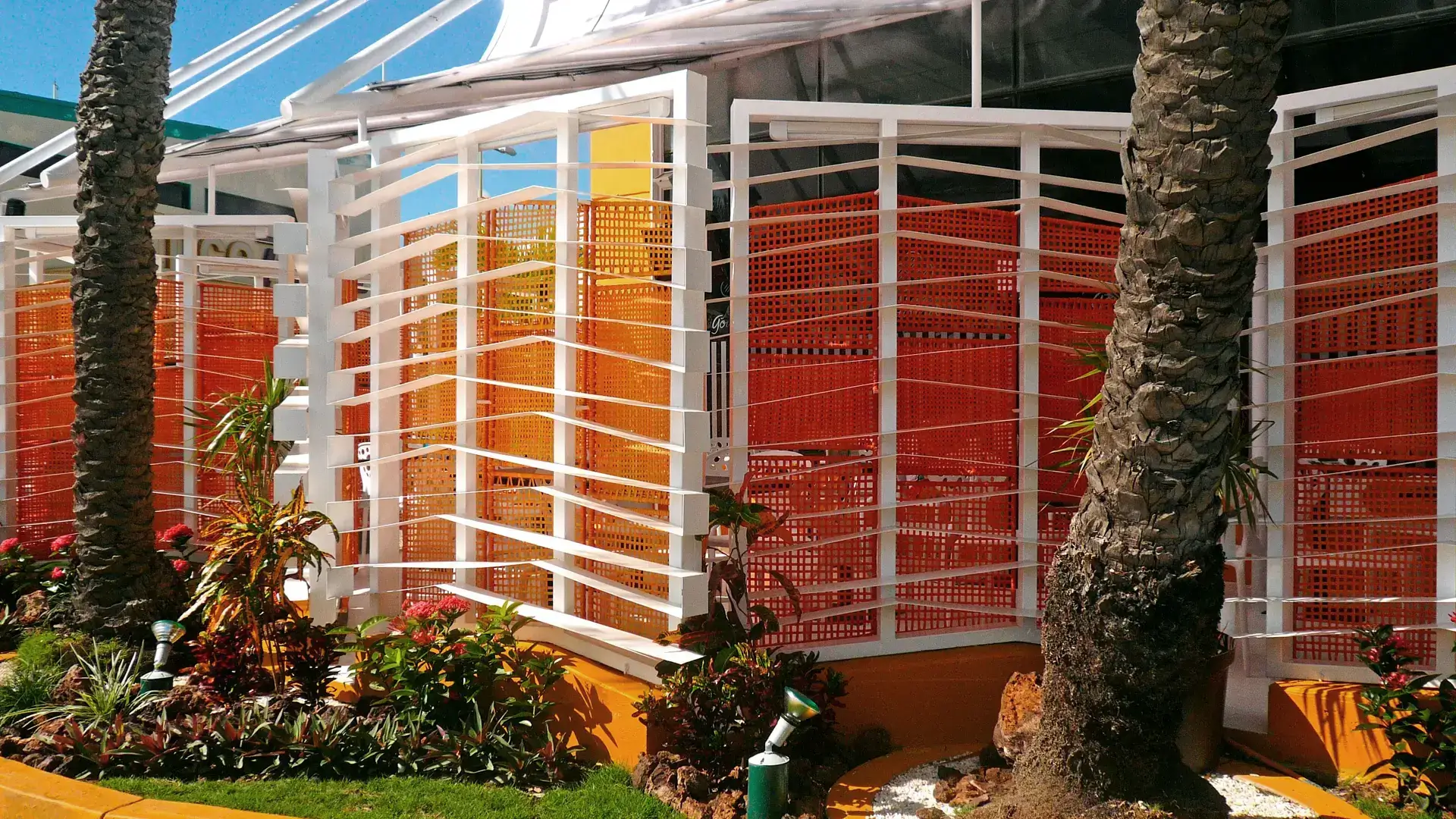 Fachada de celosía metálica blanca y mimbre naranja. Diseño de arquitectura bioclimática para un restaurante tropical.