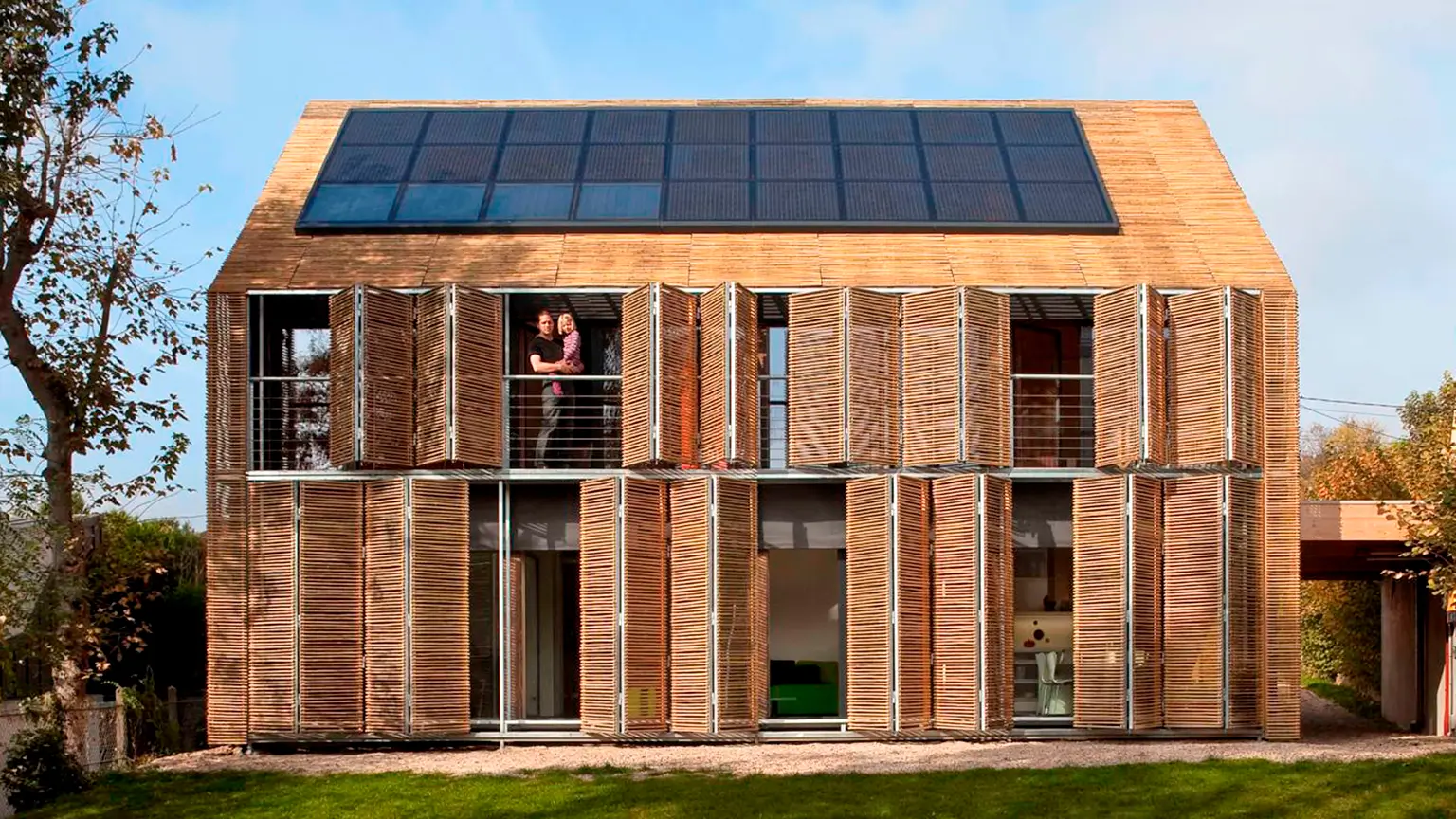 Casa moderna revestida de bambú en Francia con paneles solares, balcón y celosías plegables.