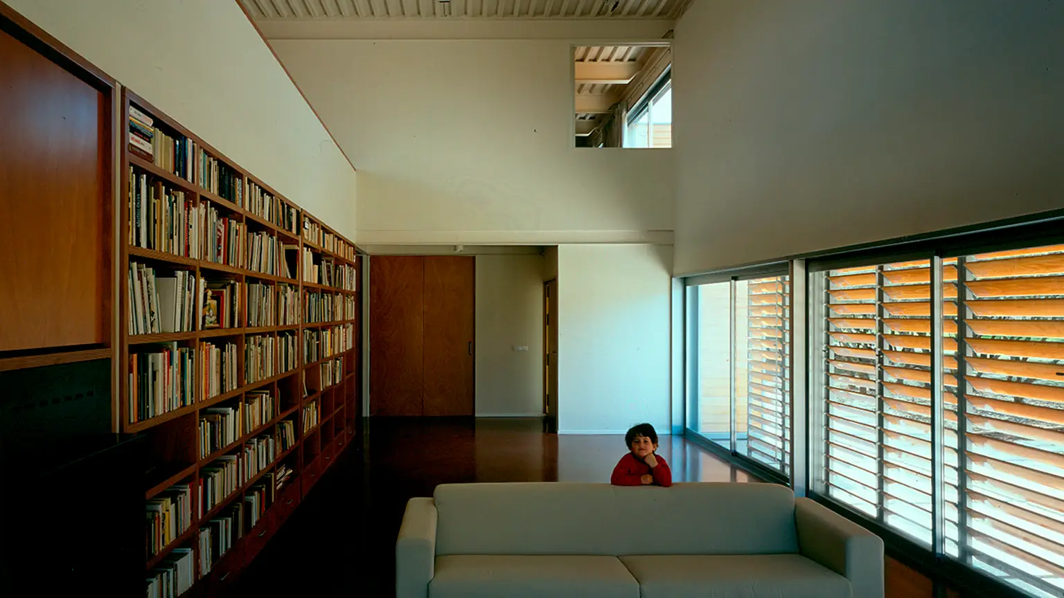 Salón a doble altura de la casa moderna del pintor Luis Gordillo en Madrid, con estantería y celosías, de Ábalos y Herreros.